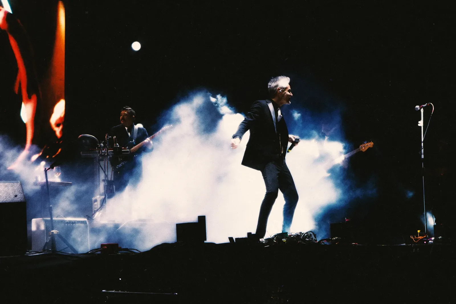 Un cantante avanza sobre el escenario entre humo y luces durante una presentación de Dängo.